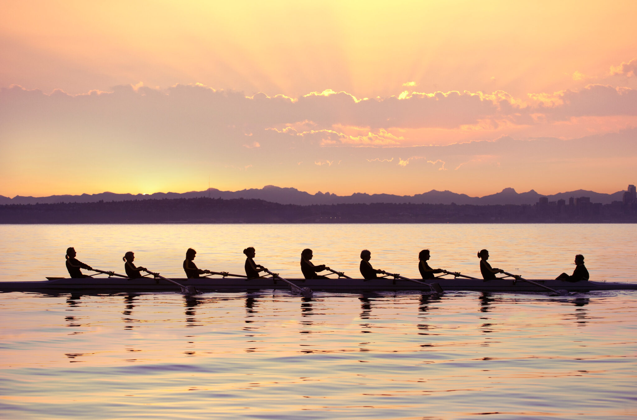 Team rowing boat in bay